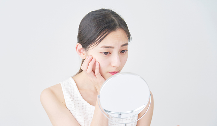 画像：顔を触って悩んでいる女性の画像