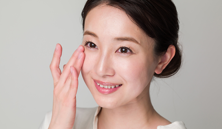 画像：笑顔で目元を触る女性の画像