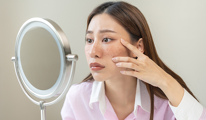 画像:鏡で目元をチェックする女性